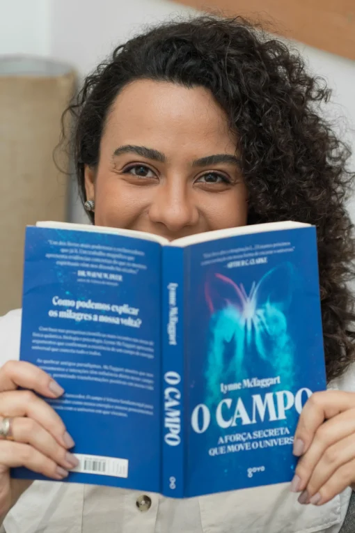 Débora Lucas segurando o livro "O Campo", em um momento de leitura e aprofundamento em desenvolvimento pessoal.